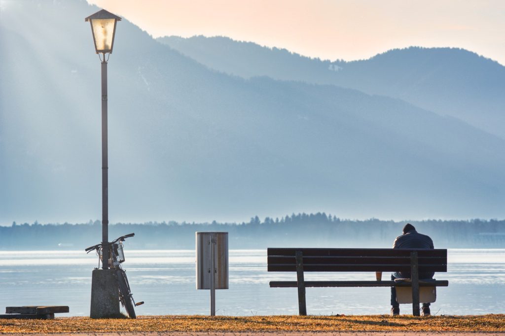 Man sat alone on a bench staring out at the lake